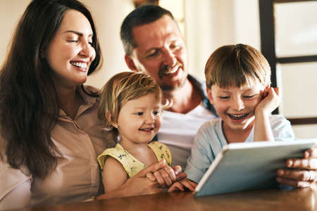 The internet is filled with fun family friendly activities. a young family of four using a digital...