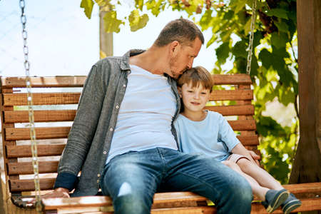 The little gestures that mean a lot. a father and his adorable son relaxing together on a garden swing.の写真素材