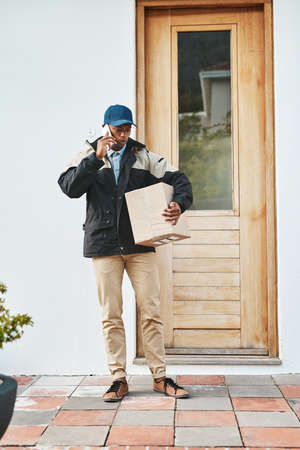 Hi, I am here with your delivery. a courier talking on a cellphone while making a delivery.