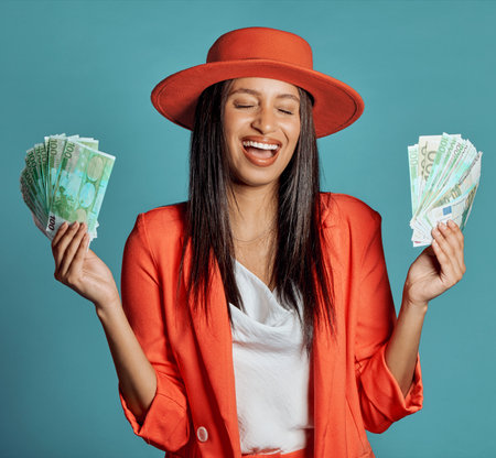 Money, currency and winning the lottery with a young woman holding cash and looking happy, excited and celebrating success. Female cheering with income, savings or a return on investment in her handsの写真素材