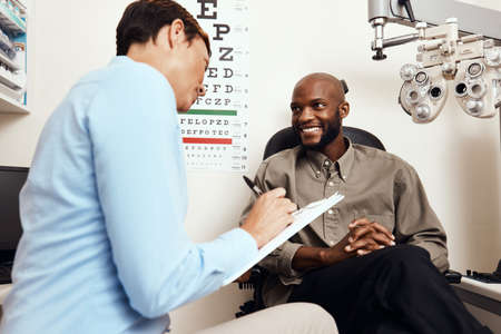 Eye test, exam or screening with an optometrist, optician or ophthalmologists with an ophthalmoscope, testing vision and eyesight. Man getting tested for prescription glasses or contact lensesの写真素材