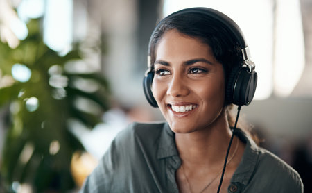 Happy face of young woman listening to music on headphones, happy and relaxed at home. Female smiling while spending her free time enjoying an audio book or learning a new language on the weekendの写真素材