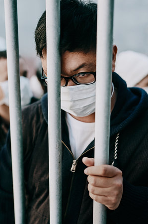 Lockdown, isolation and covid travel ban with a man in a mask behind bars during an international...