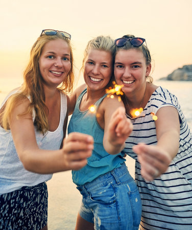 Our friendship will never lose its sparkle. young female best friends hanging out at the beach.の写真素材