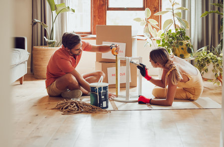Couple painting wooden table by recycle, donate and thrift furniture for a new home improvement project in new apartment. Creative and DIY man and woman with reusable objects, decorating their houseの写真素材