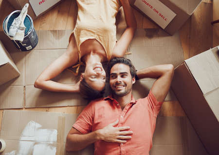 Home improvement, renovation and remodeling with a young couple lying on the floor together at home...