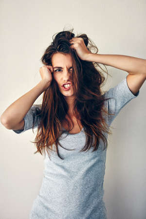 I just feel so... Studio shot of an attractive young woman posing with her hands in her hair.の写真素材