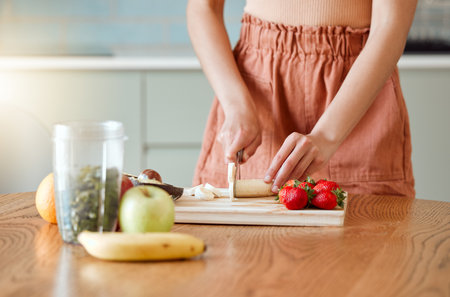 Woman making healthy smoothie for energy, nutrition and wellness with fresh organic fruit being cut, sliced and prepared. Delicious detox drink, wholesome diet and cleanse with vitamins and nutrientsの写真素材