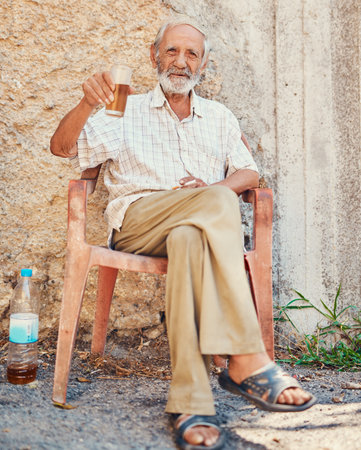 Welcome to the town I grew up in. Portrait of a senior man drinking and smoking outside on the sidewalk of an ancient city.の写真素材