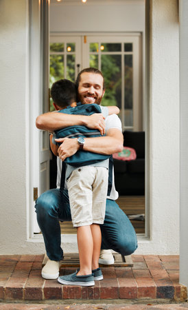 Hugging, love and care between a father and son bonding outdoors at their family home. Loving, positive and smiling man embracing his little boy. Happy male showing his child affection while playing.の写真素材