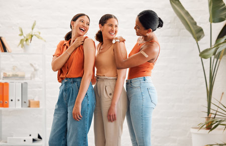 Female friends after receiving covid vaccine, happy and smiling, approving the immunity injection showing bandaid plaster arms. Diverse women recommend booster jab for protection from corona virus.の写真素材