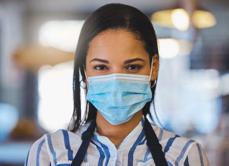 Startup, coffee shop and restaurant cafe businesswoman with covid face mask, entrepreneur, worker or barista. Closeup of professional business owner, manager or employee working after the pandemicの写真素材