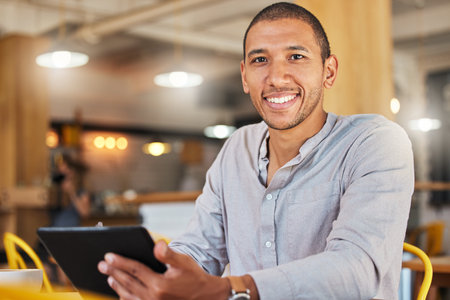 Freelancer entrepreneur or designer working online holding digital tablet, sitting in cafe or restaurant. Successful businessman with flexible schedule doing remote work on internet in coffee shop.の写真素材