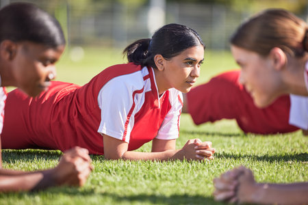 Women soccer players in a team doing the plank fitness exercise in training together on a practice sports field. Healthy female group of young athletes doing a core strength workout using teamworkの写真素材