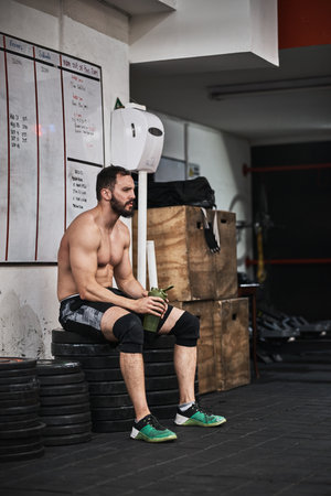 Working out is not easy, sometimes you need a break. a young man taking a break from a workout in a gym.の写真素材