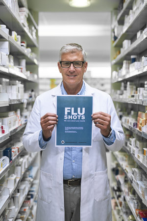 Come get your shots here. Portrait of a mature male pharmacist holding up a sign indicating that you can get flu shots there.の写真素材
