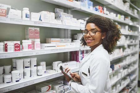 Time to take your meds. Portrait of a cheerful young female pharmacist holding a digital tablet while looking at the camera in a pharmacy.の写真素材