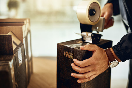 Weve got your package sealed, safe and secure. Closeup shot of a delivery man sealing a box with...