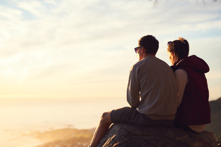 Logging out for the weekend. Rearview shot of a young couple admiring the view from the top of a mountain.の写真素材