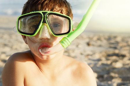 Lets get snorkelling. Portrait of a little boy wearing a mask and snorkel at the beach.の写真素材