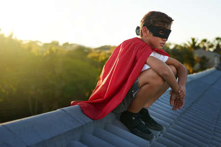 Crime never sleeps and neither does he. a young boy in a cape and mask playing superhero outside.