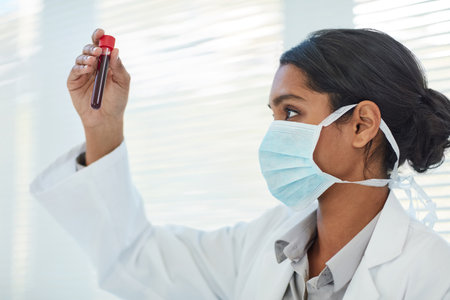 Ensuring her findings are as accurate as possible. a young female scientist examining a test tube in a lab.の写真素材