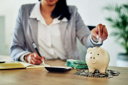 Finance, planning and saving with budget tracking, counting personal finances and family money management. Woman calculating cash and coins in piggy bank for future bills, retirement or holiday fundsの写真素材