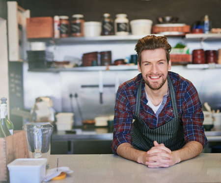You ready to order. Portrait of a young barista working behind the counter in his coffee shop.