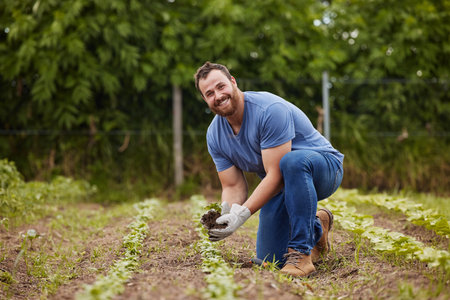 Farmer planting plants or vegetable crops on an organic and sustainable farm and is happy for his...