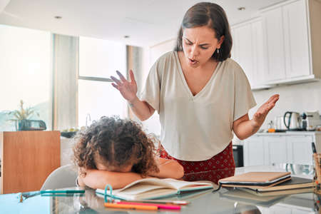 Autism, frustrated and bad mental health behavior by child and frustrated mother during homework. Annoyed, abuse parent angry with crying child suffering from ADHD and hiding, afraid and depressedの写真素材