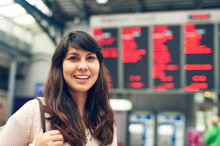 My flights leaving soon. Cropped portrait of an attractive young woman standing at an arrivals and departures board in the airport.の写真素材