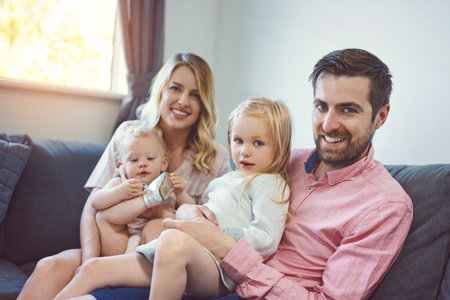 Family is first priority in our home. Portrait of an adorable young family of four relaxing together...