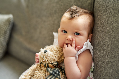 The innocence of an infant. Portrait of an adorable baby girl playing with a teddybear at home.の写真素材