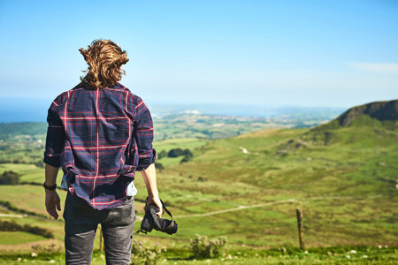 Go where there is only nature and find yourself. Rearview shot of an unrecognizable man looking at the view outdoors.の写真素材
