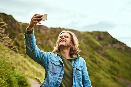 Selfie for the people back home. a handsome man taking a selfie outdoors.の写真素材