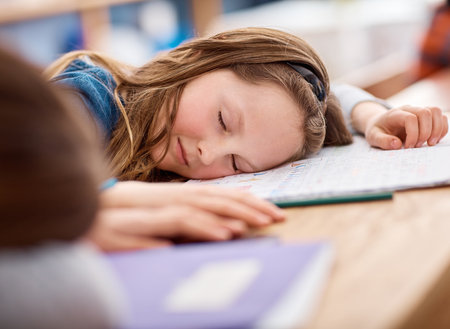I just need to rest my brain for a bit. an elementary school girl sleeping on her desk in class.の写真素材