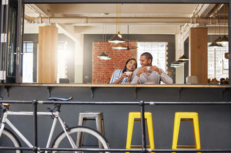 Happy couple sitting at a coffee shop on a fun date at a cafe or restaurant with peace. Woman and...
