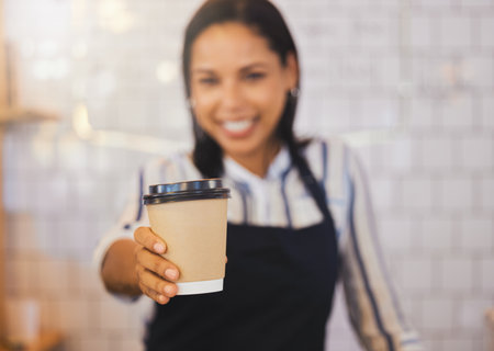 Coffee shop, closeup and barista holding cup and giving it to the customer at cafe. Female restaurant service worker in beverage business. Small business, management and food worker serving client.の写真素材