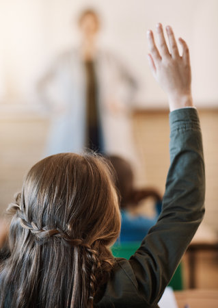 Taking part in class activities. an unrecognizable elementary school girl hand raised in the classroom.の写真素材