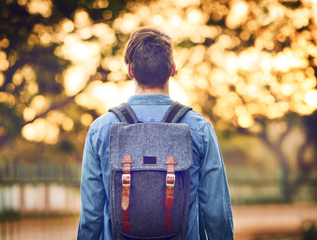 Gazing into autumn. Rearview shot of an unrecognizable man wearing a backpack during autumn.