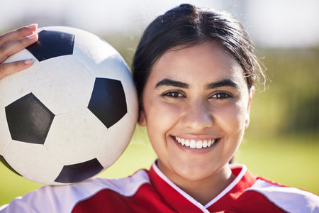 Training, football and portrait of a sporty woman face and soccer ball, enjoying sport and a healthy lifestyle at a field or park. Happy player having fun with fitness, being active and carefreeの写真素材