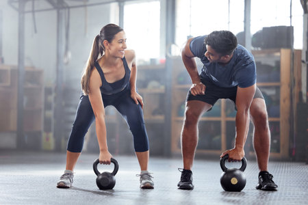 Strong, wellness couple doing kettlebell weight exercise, workout or training inside a gym. Happy...
