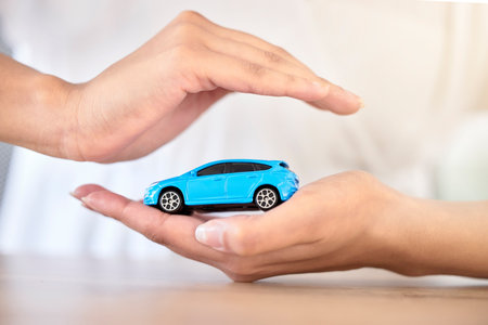 .Car insurance, finance and travel safety model size motor vehicle covered, security and protected by hands. Financial, toy automobile and transportation loan assurance for trustworthy service help.の写真素材