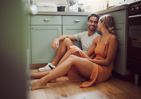 Couple, in love and on kitchen floor looking into their eyes on luxury real estate. Man, woman and communication and a conversation in a new home, house or room before breakfast with family.の写真素材
