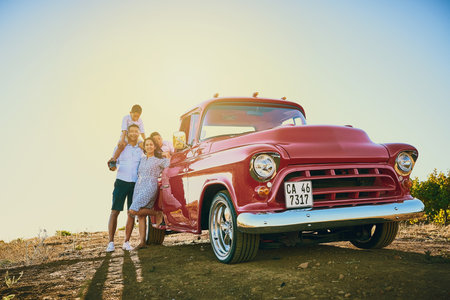 Going for a ride with the family. a cheerful family posing for a portrait together outside next to a red pickup truck.の写真素材