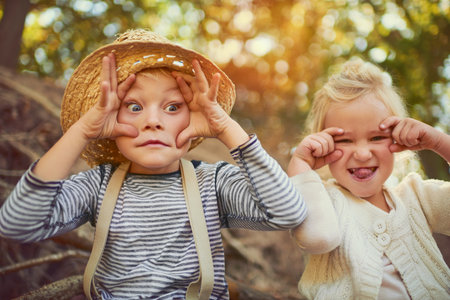 Showing off their funny character. Portrait of two little children playing together outdoors.の写真素材
