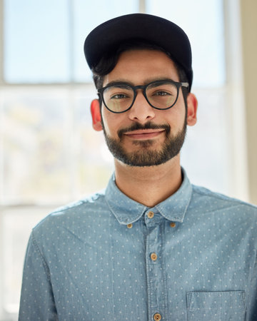 Meet the walking definition of cool and casual. Portrait of a confident young man standing indoors.の写真素材