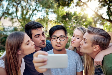 Share the love. a young group of friends taking selfies while enjoying a few drinks outside in the summer sun.の写真素材