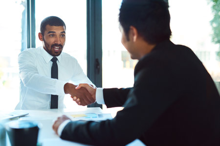 Glad to have you on our team. a two businessmen shaking hands in the workplace.の写真素材