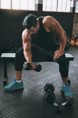 Im the result of my dedication. a young man working out with dumbbells at the gym.の写真素材